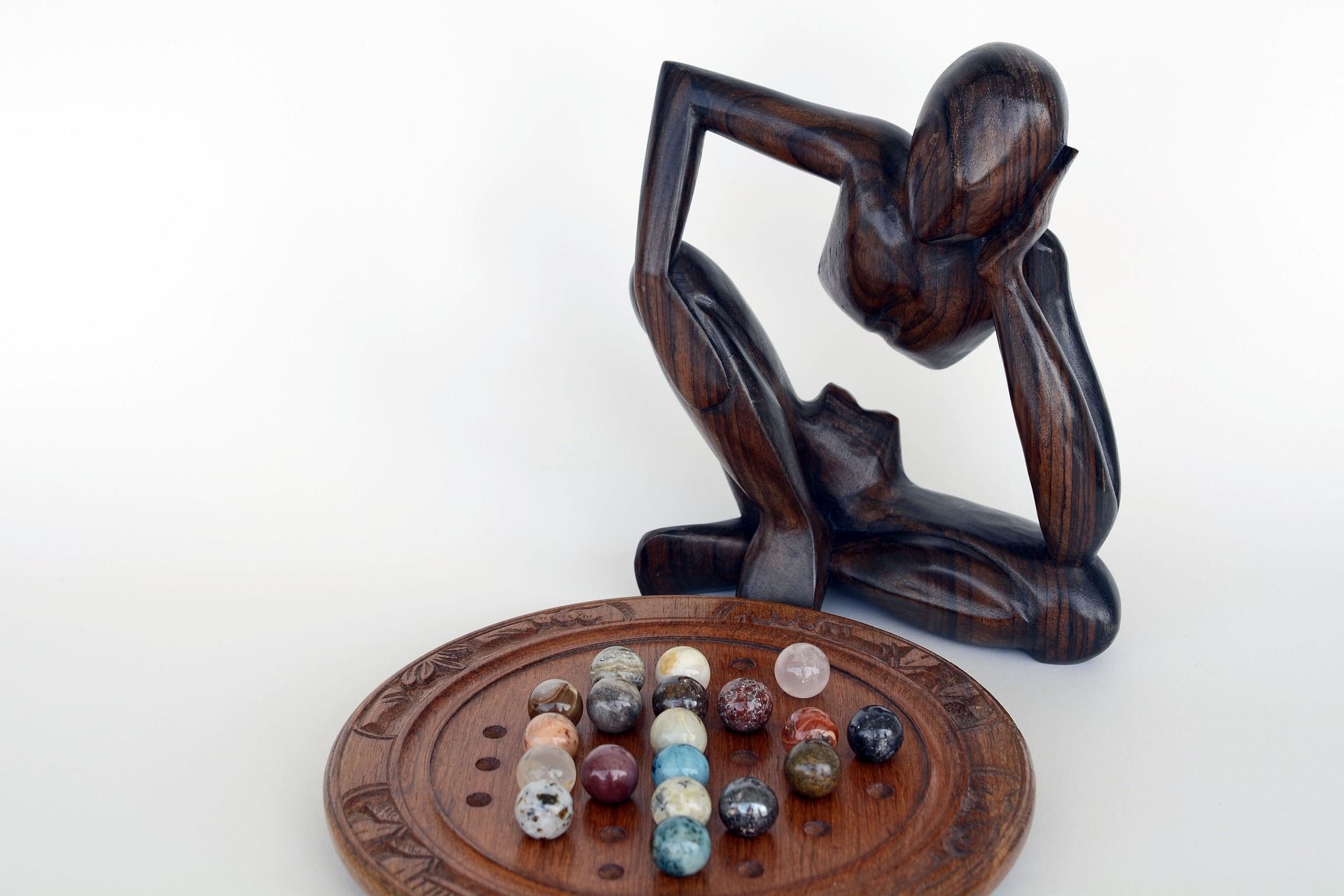 Abstract wooden sculpture gazing at marbles, symbolizing the debunking of business development myths.