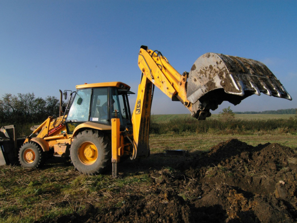 Empty property under development with a digger at work, symbolizing the process of mastering real estate.