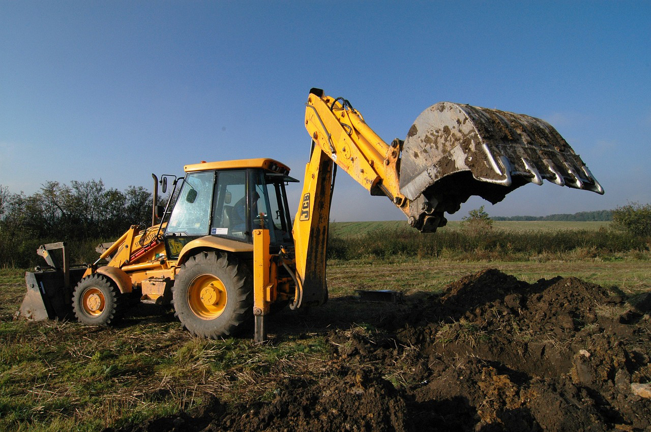 Empty property under development with a digger at work, symbolizing the process of mastering real estate.