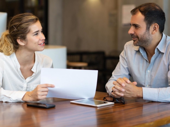 Two professionals in a meeting call, diligently reviewing real estate documents.